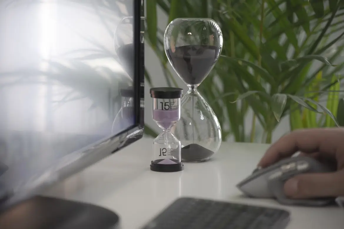 person working remotely beside clear hour glass